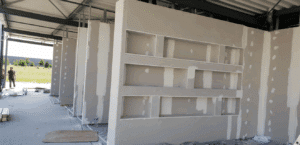 Construction intérieure sous abri avec murs en plaques de plâtre (gypse) fraîchement montés, présentant des niches intégrées en cours de jointoiement.